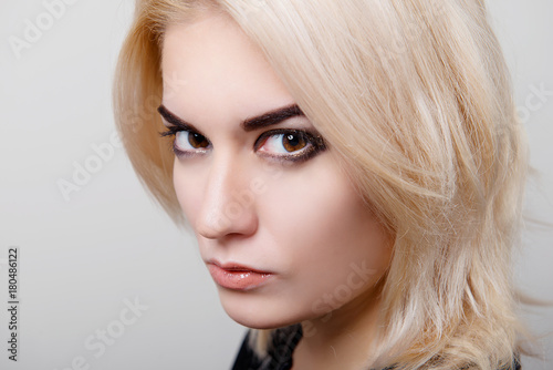 Blonde girl with bright makeup and clean skin on a white isolate close-up