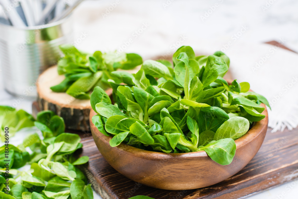 Lettuce leaves in a wooden bowl and on a table Lettuce leaves in a wooden bowl and on a table