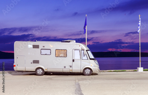 Motorhome RV and campervan are parked on a beach. Motor home caravans are parked on a parking space for RV vehicles by Aegean sea in Greece. Night scenery.