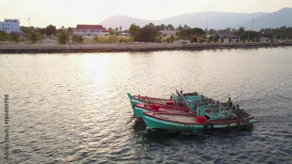 Aerial shot of fishing boast on the Prek Kampong river in Kampot, Cambodia with Bokor National Park in the distance at sunset. Aerial shot of fishing boast on the Prek Kampong river in Kampot, Cambodia with Bokor National Park in the distance at sunset.