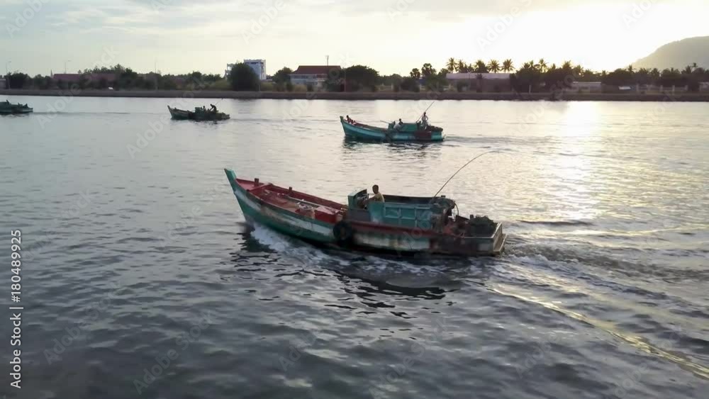 Aerial shot of fishing boast on the Prek Kampong river in Kampot, Cambodia with Bokor National Park in the distance at sunset. Aerial shot of fishing boast on the Prek Kampong river in Kampot, Cambodia with Bokor National Park in the distance at sunset.