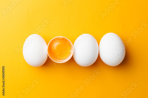 Leinwand Poster Weiße Eier und Eigelb auf dem gelben Hintergrund. Draufsicht