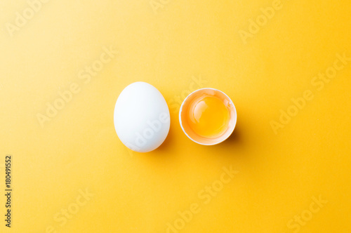White egg and egg yolk on the yellow background. topview