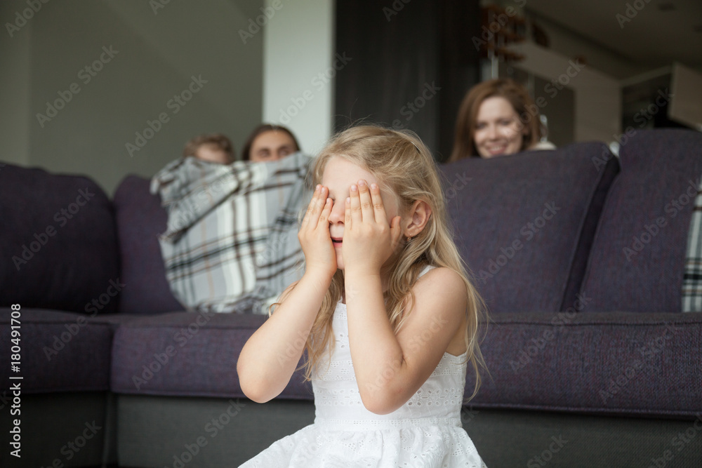 Little girl closing eyes covering face with hands playing hide and seek