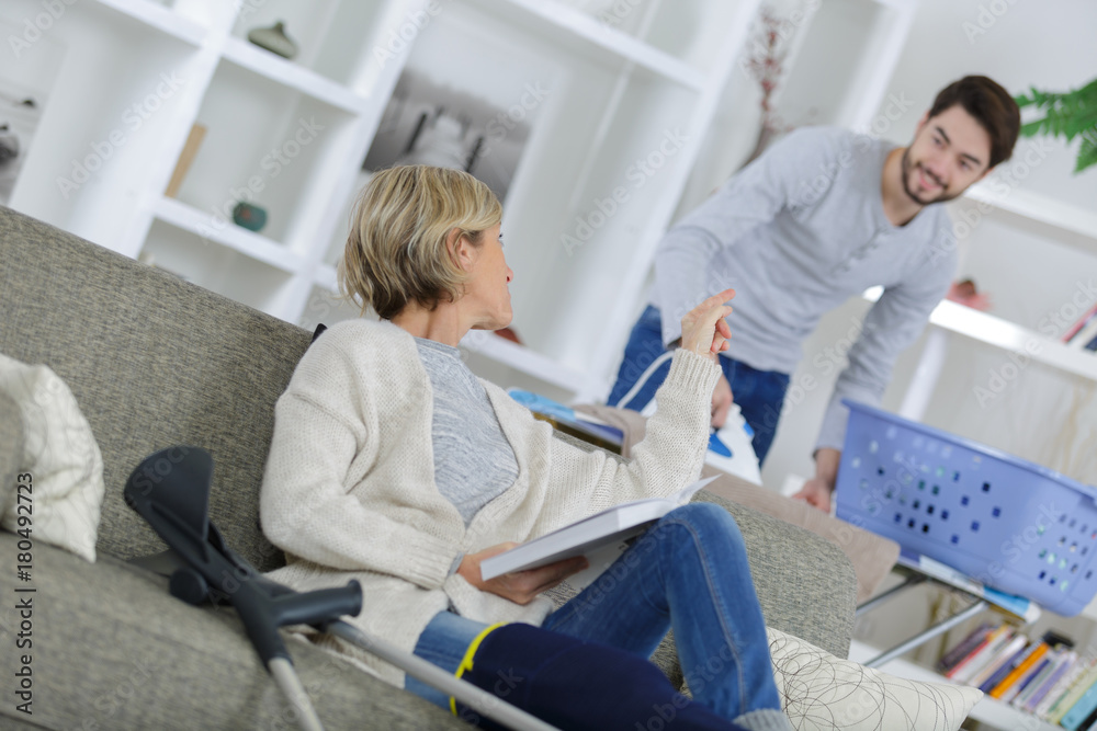 woman with plastered leg sitting on couch asking for help woman with plastered leg sitting on couch asking for help
