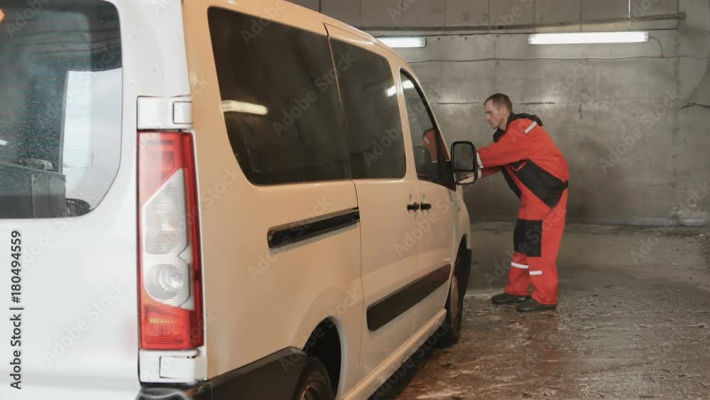 Professional car washman sprays the wax at surface of car Professional car washman sprays the wax at surface of car