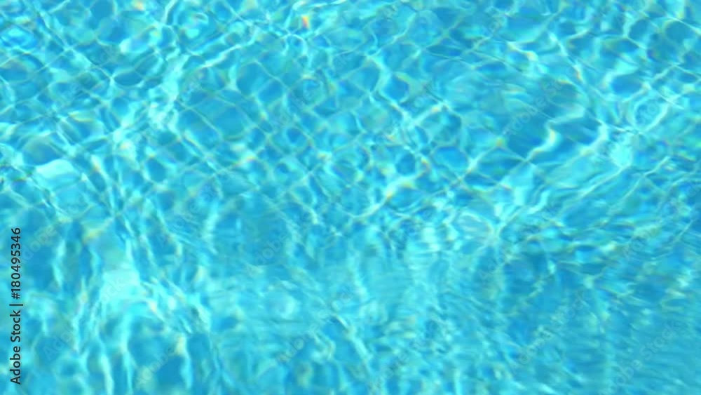 Blue water in swimming pool. Waves and patches of sunlight appears on the bottom of the pool. Glares blinks and reflections on clear water. Blue water in swimming pool. Waves and patches of sunlight appears on the bottom of the pool. Glares blinks and reflections on clear water.