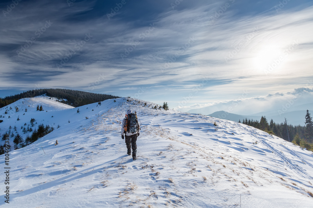 Man is backpacking in winter mountains