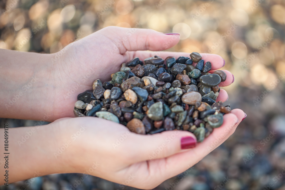 Female hands holding colorful gravels collected from the beach Female hands holding colorful gravels collected from the beach