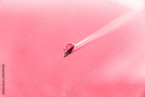 on the tip of a needle from a syringe drop of liquid