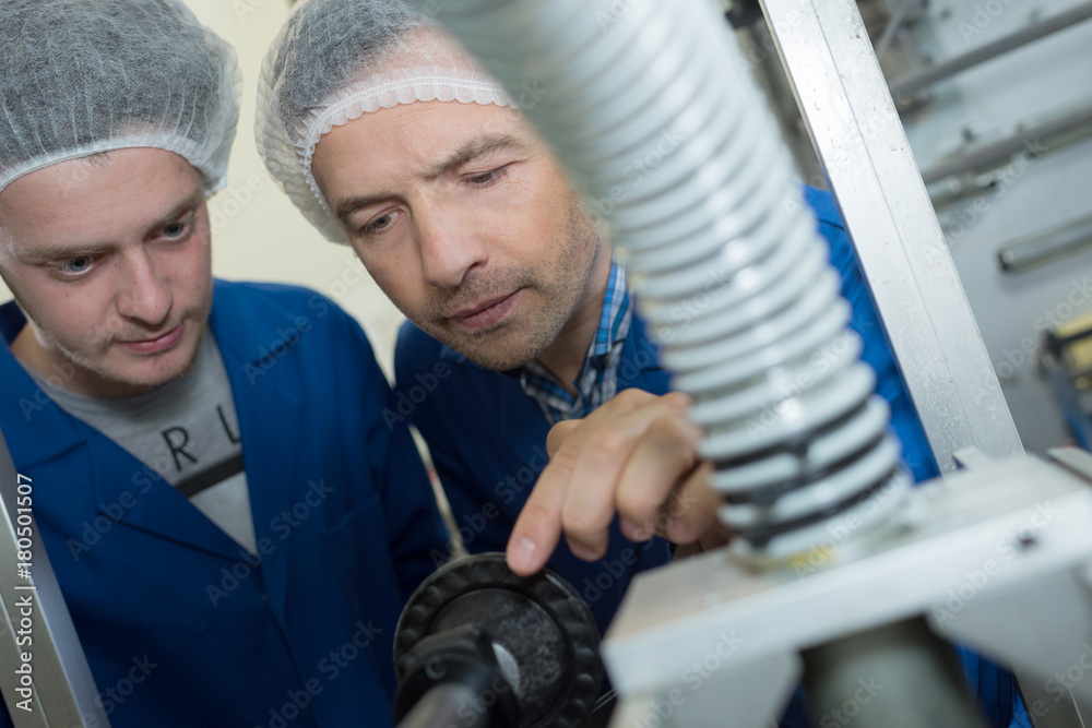 two male wearing safety hair net working at a factory two male wearing safety hair net working at a factory