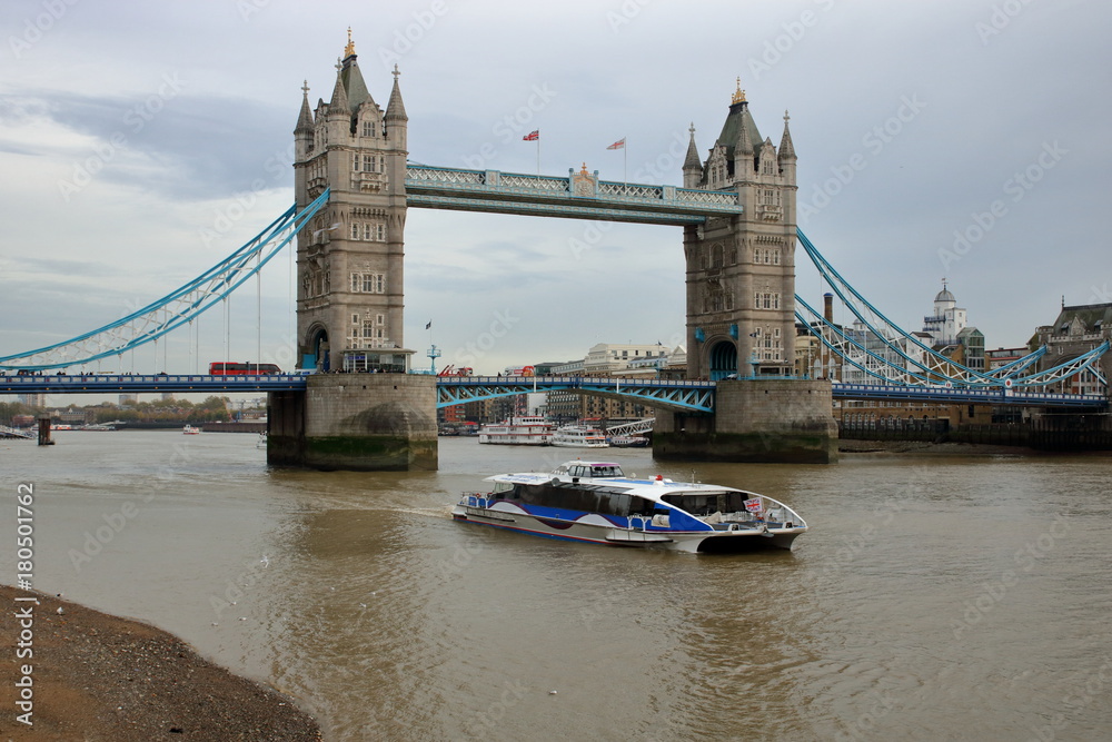 Fototapeta premium Widok z brzegu Tamizy na rzekę i most Tower Bridge, mała łódź pasażerska na rzece