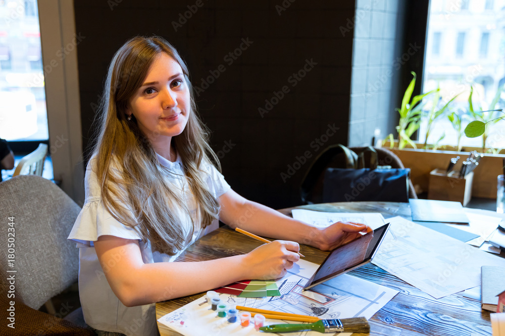 Girl working on the interior project with tablet and artist tools Girl working on the interior project with tablet and artist tools