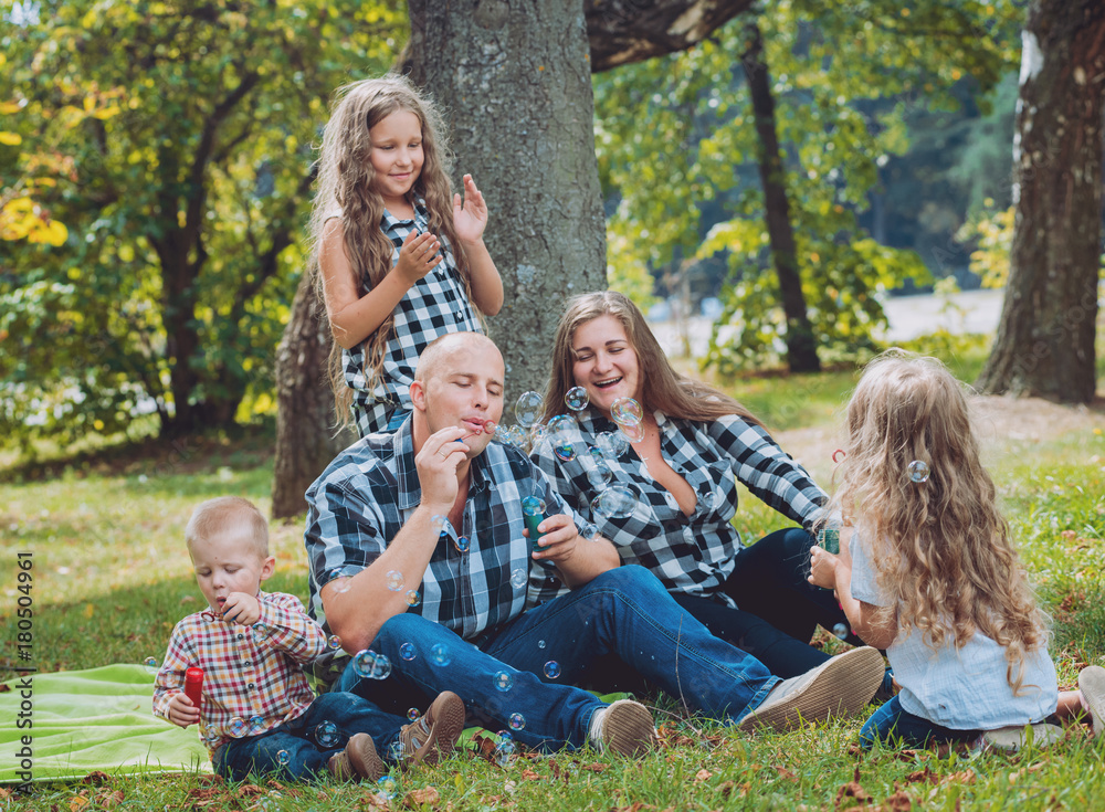 Fototapeta premium Young family with cheerful children in the park