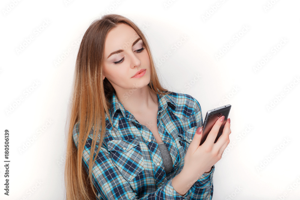 Naklejka premium Portrait of a young adorable blonde woman in blue plaid shirt enjoying having emotional conversation on smartphone.
