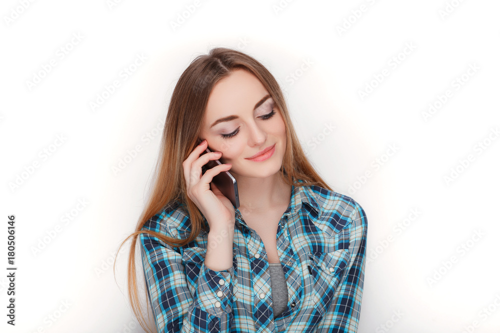 Portrait of a young adorable blonde woman in blue plaid shirt enjoying having emotional conversation on smartphone. Portrait of a young adorable blonde woman in blue plaid shirt enjoying having emotional conversation on smartphone.