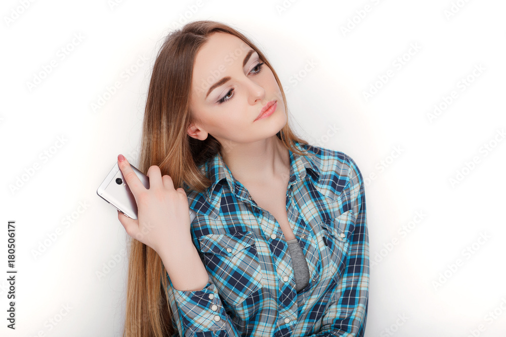 Portrait of a young adorable blonde woman in blue plaid shirt enjoying having emotional conversation on smartphone. Portrait of a young adorable blonde woman in blue plaid shirt enjoying having emotional conversation on smartphone.