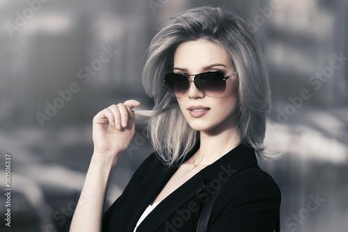 Tela Young fashion blond business woman in sunglasses walking in city street