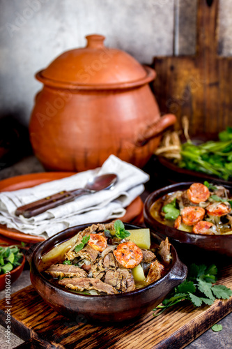Chilean Ajiaco. Latin American food. Ajiaco - traditional chilean soup with grilled meat, onion and potato served in clay plates photo