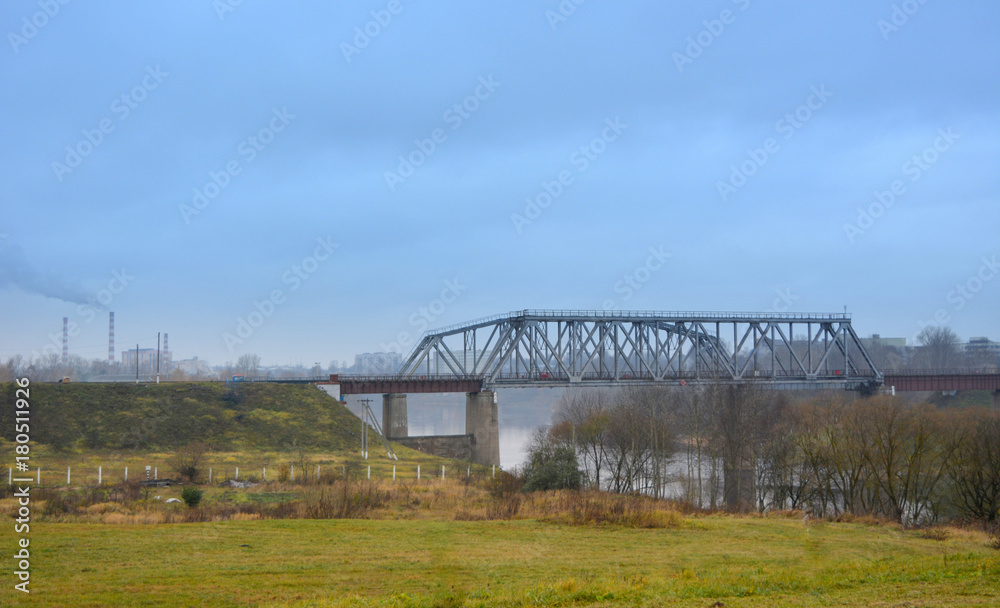 beautiful city view, autumn landscape: railway bridge over the river, pipes and green grass