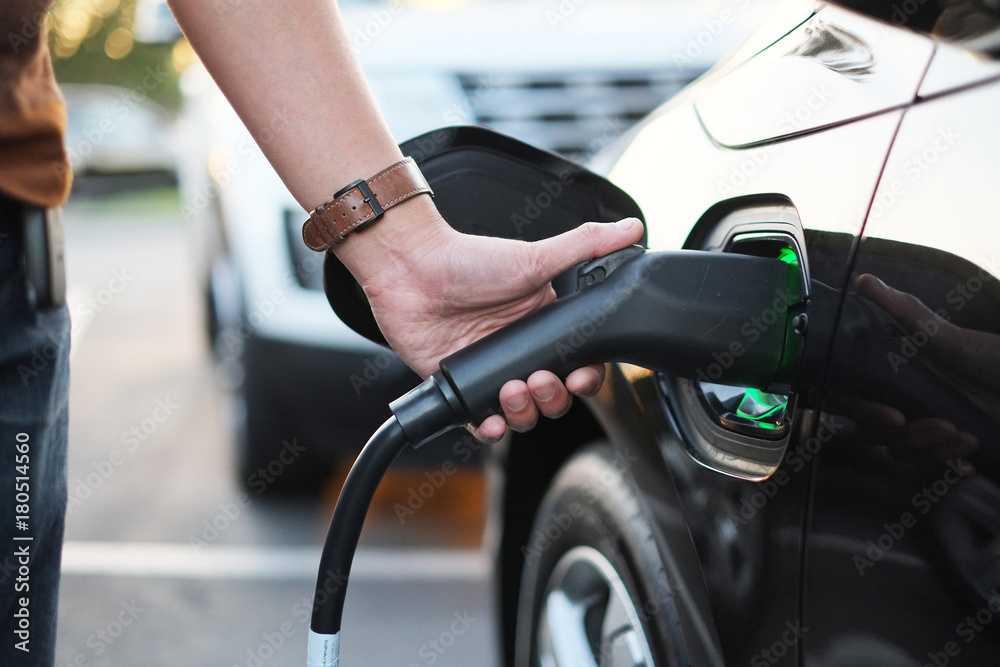A man at the power supply for electric car charging station. ch A man at the power supply for electric car charging station. ch