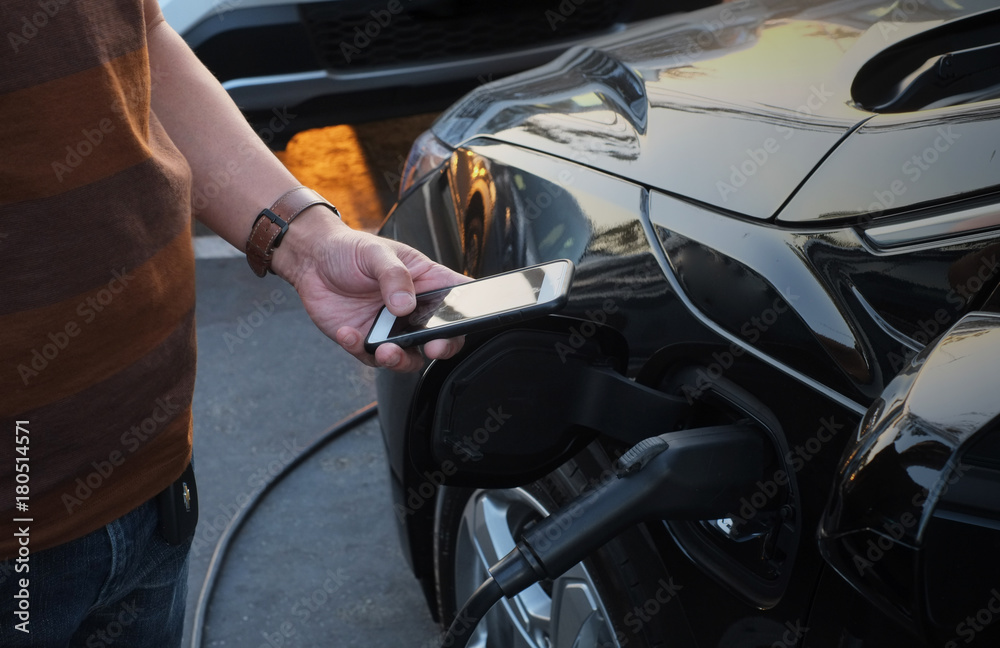 A man at the power supply for electric car charging station. ch A man at the power supply for electric car charging station. ch