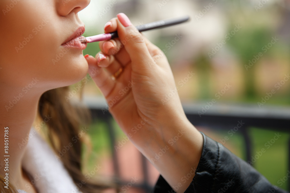 Process of making makeup. Make-up artist working with lips stick on model lips. Portrait of young woman in beauty saloon. Applying tone to skin. Process of making makeup. Make-up artist working with lips stick on model lips. Portrait of young woman in beauty saloon. Applying tone to skin.