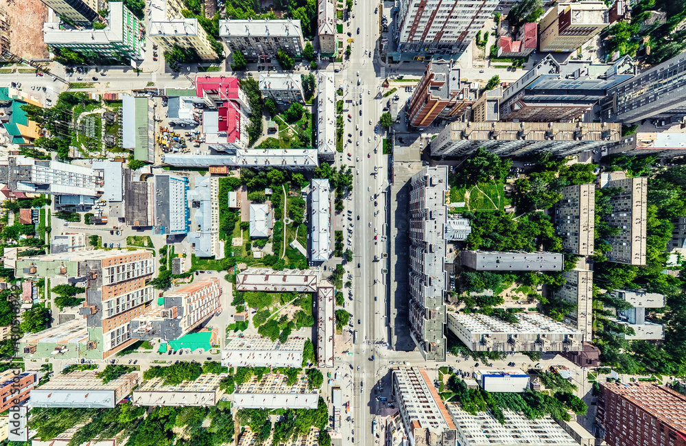 Fototapeta premium Aerial city view with crossroads and roads, houses, buildings, parks and parking lots, bridges. Helicopter drone shot. Wide Panoramic image.
