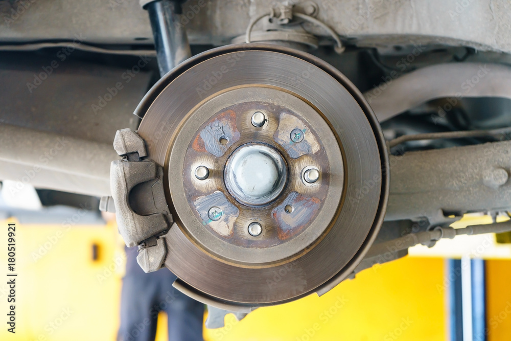 Closeup disc brake of the vehicle for repair, in process of new tire replacement. Car brake repairing in garage