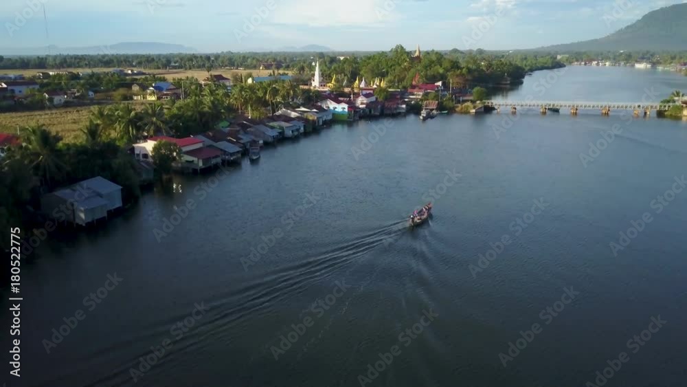 Aerial shot of fishing boat on the Prek Kampong river in Kampot, Cambodia with Bokor National Park in the distance. Aerial shot of fishing boat on the Prek Kampong river in Kampot, Cambodia with Bokor National Park in the distance.