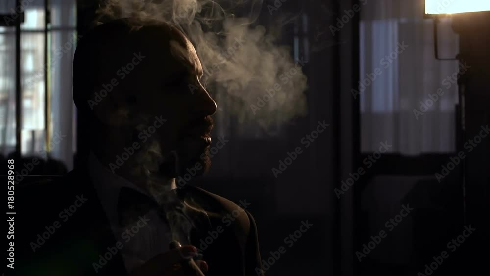 Silhouette serious man with a cigar who blows a lot of smoke, slow motion. Silhouette serious man with a cigar who blows a lot of smoke, slow motion.