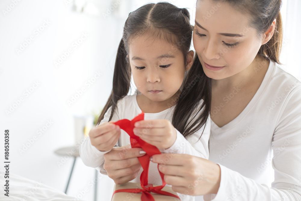 Attractive Asian Girl received a present from her Mom. Woman try to open Gift for her daugther. Happy Family Concept. Attractive Asian Girl received a present from her Mom. Woman try to open Gift for her daugther. Happy Family Concept.