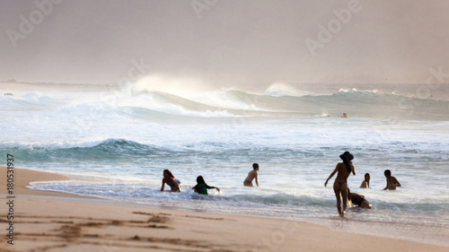 Scenic seascape sunset and silhouetted people at Banzai Pipeline beach on North Shore of Oahu, Hawaii, USA.