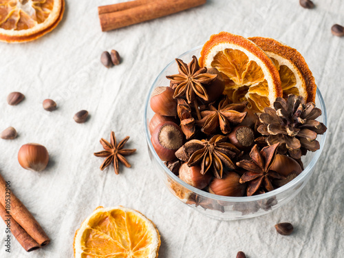 Winter ingredients nuts, cones, oranges, cinnamon star anise in a bowl. Rustic style