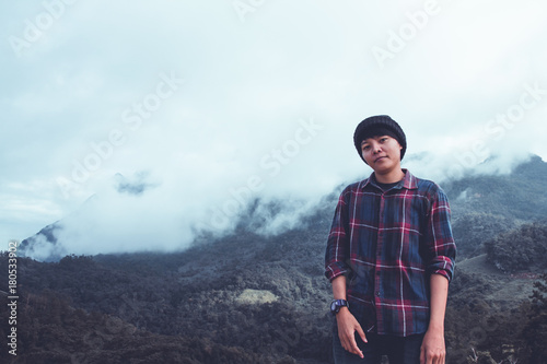 Asian young man in Scottish shirt and black hat hiking at mountain peak above clouds and fog Hiker outdoor. Doi Luang Chiang Dao Chiangmai Province,In morning. photo