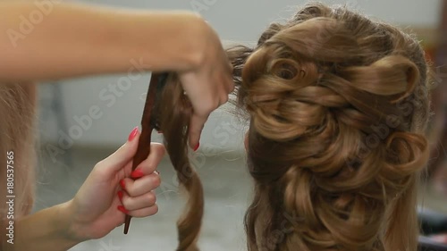 A professional stylist makes a hairstyle for the model. Fashion world.
