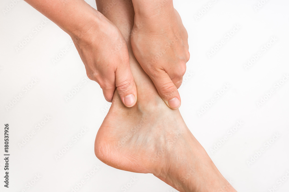 Woman with ankle pain holding her aching leg Woman with ankle pain holding her aching leg