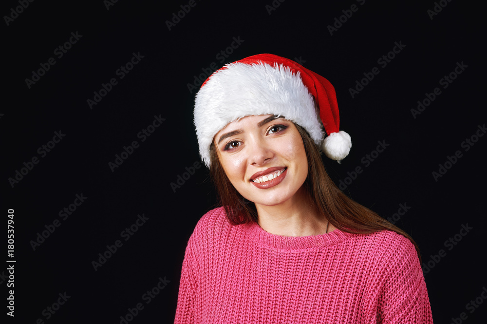 Young woman in Santa hat on a dark background Young woman in Santa hat on a dark background