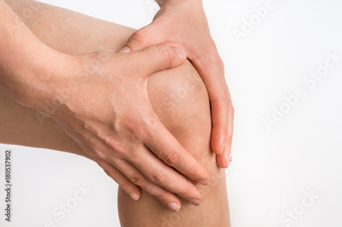 Woman with knee pain is holding her aching leg