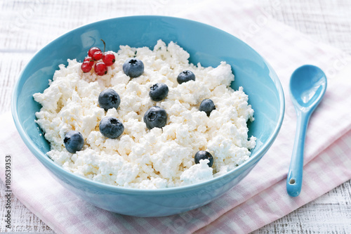 Organic curd cheese, farmer's cheese or cottage cheese in blue bowl. Closeup view. Healthy diet, dairy products concept