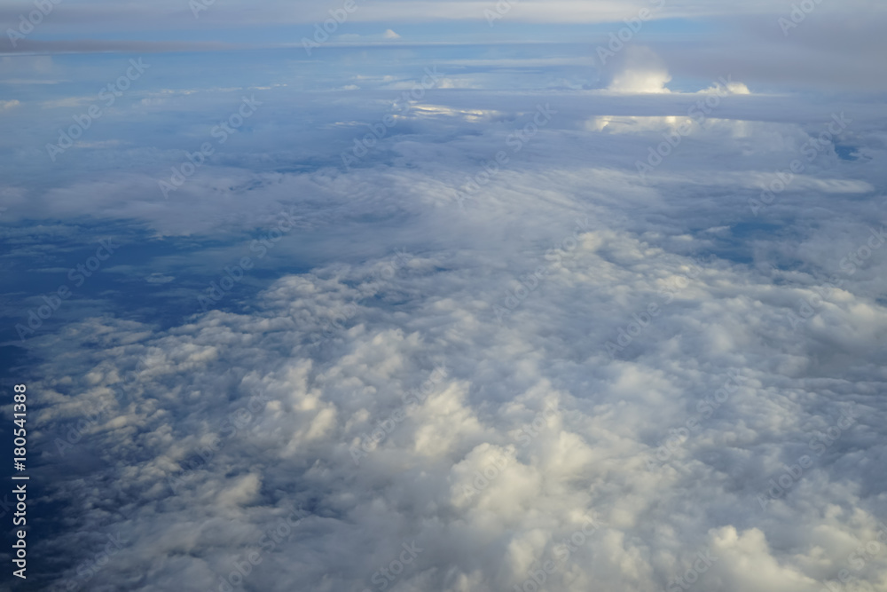 View of beautiful abstract soft white cloudscape with shades of blue sky background from flying plane window