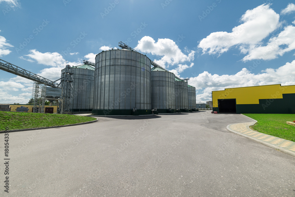 The modern granary. High metal silos for storage of wheat and barley. Sunny day, the blue sky. The modern granary. High metal silos for storage of wheat and barley. Sunny day, the blue sky.