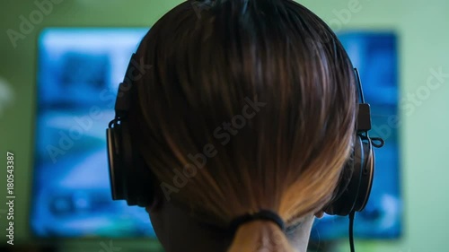 Gamer Girl w/ Headphones. Female plays an FPS videogame while wearing headphones. photo