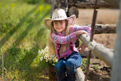 Cute fermer beautiful girl cowboy in jeans enjoying summer day in village life with flowers happyly smiling.