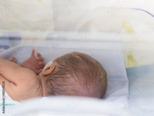 Sick newborn baby, infant in an incubator after preterm birth at intensive care unit 