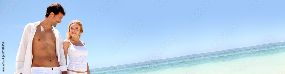 Couple walking on white sandy beach - banner template web Couple walking on white sandy beach - banner template web