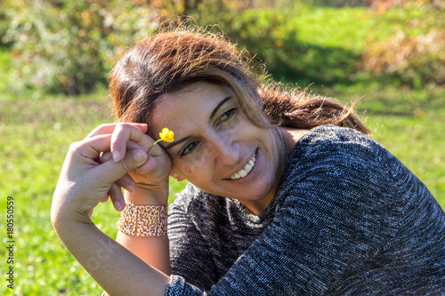 Frau mit Blümchen draußen auf Wiese genießt Sonne