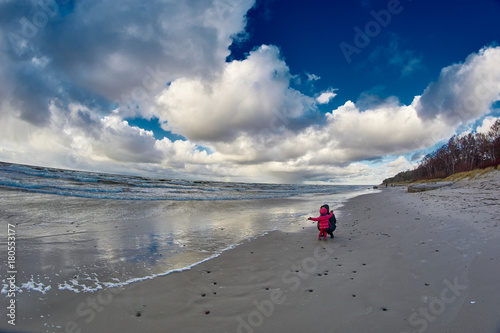 mother is playing with girl child daughter at empty beach in autumn