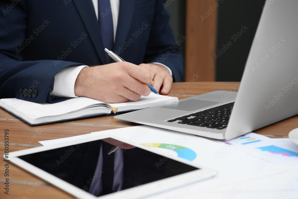 Young marketing manager making notes while sitting at table Young marketing manager making notes while sitting at table