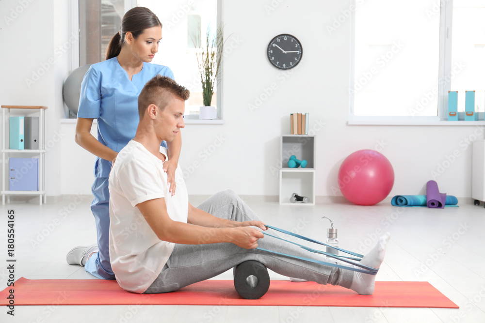 Physiotherapist working with young male patient in clinic Physiotherapist working with young male patient in clinic